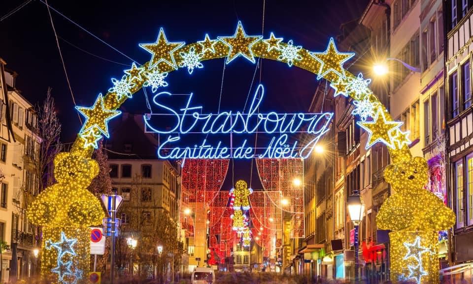 Strasbourg Christmas markets light up sign with stars, and Christmas decorations on the buildings.