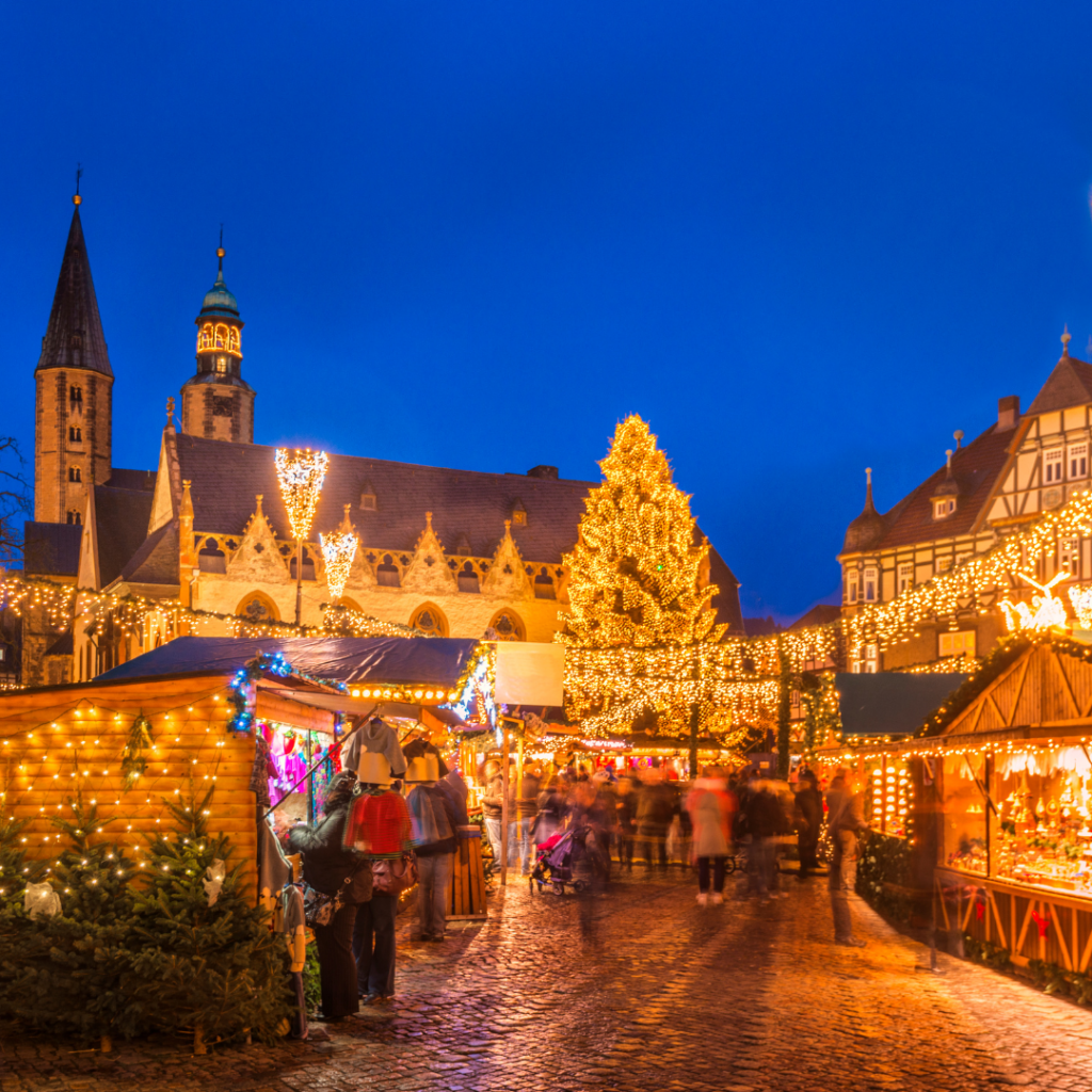 European Christmas market buildings decorated with twinkling lights and people walking around.