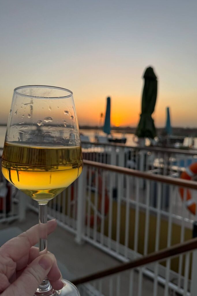 Holding wine glass with the sun setting on the Nile aboard AmaLila river cruise ship